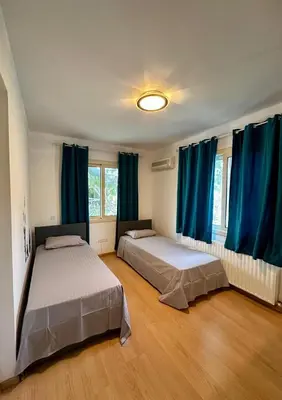 two beds in a room with blue curtains at Villa Eva in Mazotos