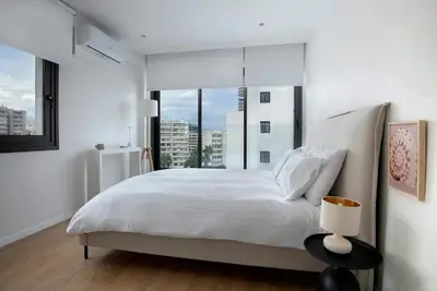a white bedroom with a large bed and a window at Luxury Beachfront Apartment in Limassol