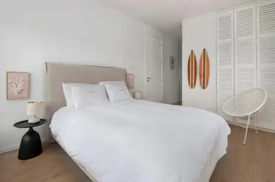 a white bedroom with a large bed and a chair at Luxury Beachfront Apartment in Limassol