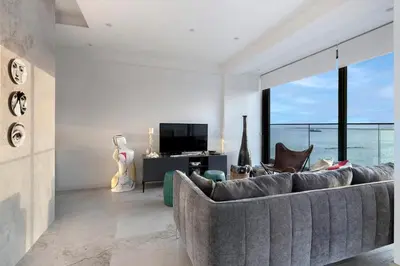 a living room with a gray couch and a television at Luxury Beachfront Apartment in Limassol