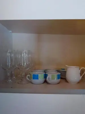 a shelf with bowls and plates and wine glasses at Beautiful 1-Bed House in Aglantzia