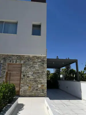 a white house with a door and a stone wall at City Napa Seaview Villas - Villa 2 in Ayia Napa