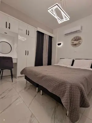 a white bedroom with a large bed and a chair at 3 rooms modern apartment close to the beach! in Larnaka