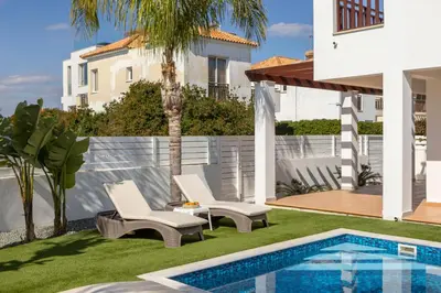 a yard with two chairs and a swimming pool at Sweet Seaview Villa in Ayia Napa