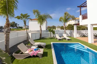 a backyard with a swimming pool and palm trees at Sweet Seaview Villa in Ayia Napa
