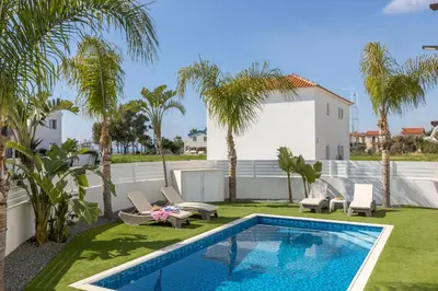 a backyard with a swimming pool and palm trees at Sweet Seaview Villa in Ayia Napa