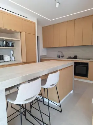a kitchen with two white chairs at a counter at Deluxe Seafront - 2 Bed in Limassol