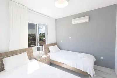 a white bedroom with two beds and a window at Mandali Villa 20 - Fully Renovated Villa in Paralimni