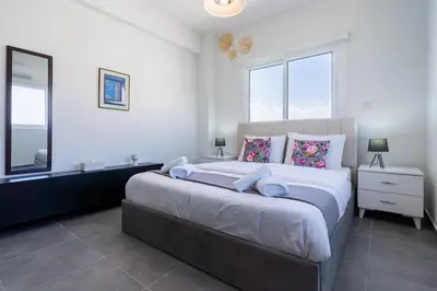 a bedroom with a large bed and two windows at Snobby 2-Bedroom Apartment in Larnaka