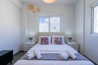 a white bedroom with a large white bed with pillows at Snobby 2-Bedroom Apartment in Larnaka