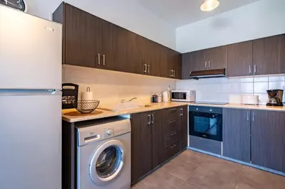 a kitchen with wooden cabinets and a washer and dryer at Snobby 2-Bedroom Apartment in Larnaka