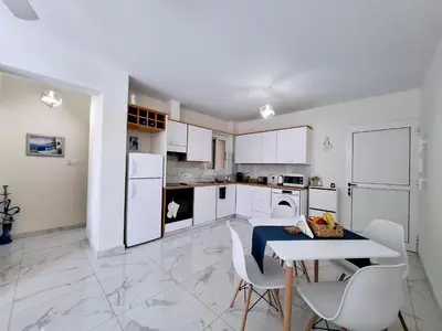 a kitchen with white cabinets and a table and chairs at Sofia`s place in Voroklini