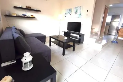 a living room with a couch and a tv at Ionian Breeze Family House Walk to Beach And Dining in Paralimni