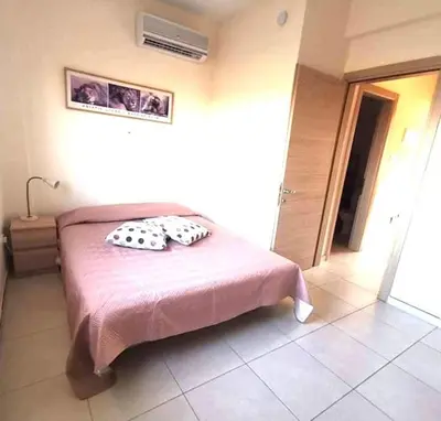 a bedroom with a pink bed with two pillows on it at Ionian Breeze Family House Walk to Beach And Dining in Paralimni