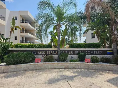 a sign in front of a building with palm trees at Mediterranean Sunrise Apartments A2 in Voroklini
