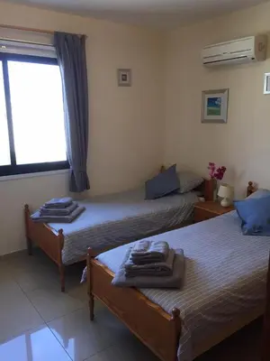 two beds in a room with a window at Mediterranean Sunrise Apartments A2 in Voroklini