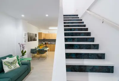 a staircase in a living room with a green couch at Beach Walk - Central, Cool, Cute, Convenient in Limassol