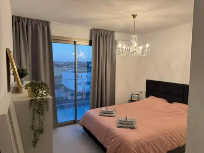 a bedroom with a bed with a chandelier and a window at Brandnew Rooftop Flat near Larnaca Mall in Larnaka