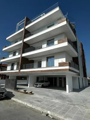 a white building with a car parked in front of it at Brandnew Rooftop Flat near Larnaca Mall in Larnaka