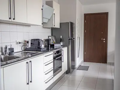 a kitchen with white cabinets and a sink and a door at Cozy sea view Apartment in Mazotos