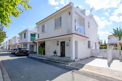 a white house with a car parked in the street at Endless Summer Beach House in Pervolia