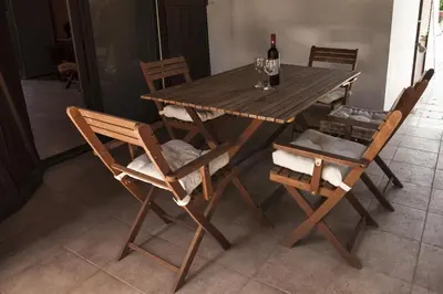 a wooden table with chairs and a bottle of wine at El Marco Villa in Pissouri