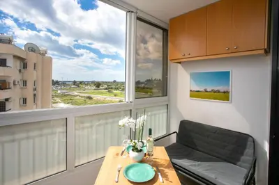 a living room with a table and a large window at Palmove Makenzy Ria Studio in Larnaka