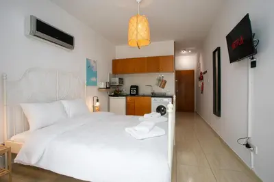 a bedroom with a white bed and a kitchen at Palmove Makenzy Ria Studio in Larnaka