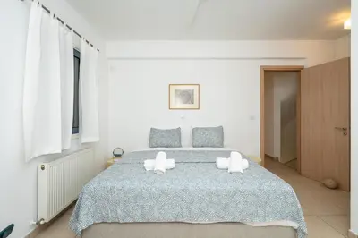 a white bedroom with a bed with two white candles on it at Niki Seaview Villa DPS27 in Protaras