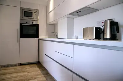 a kitchen with white cabinets and a microwave at Corina Suites & Apartments in Limassol