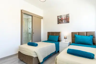 two beds in a room with white walls and blue pillows at Modern Townhouse with pool ten minutes Limassol Center in Limassol