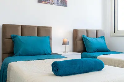 two beds with blue pillows in a room at Modern Townhouse with pool ten minutes Limassol Center in Limassol