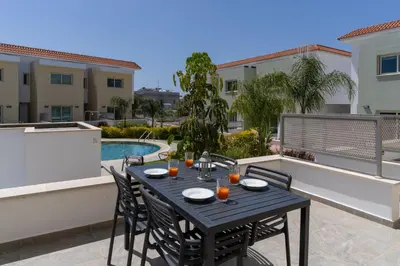 a black table and chairs on a patio with a pool at Modern Townhouse with pool ten minutes Limassol Center in Limassol