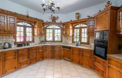 a large kitchen with wooden cabinets and windows at Aέναη in Pyrga