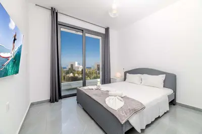 a bedroom with a bed and a large window at By The Beach - Aura Villa in Protaras