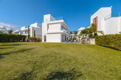 a large grassy yard in front of a white building at By The Beach - Aura Villa in Protaras