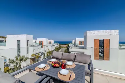 a table on a balcony with a view of the ocean at By The Beach - Aura Villa in Protaras