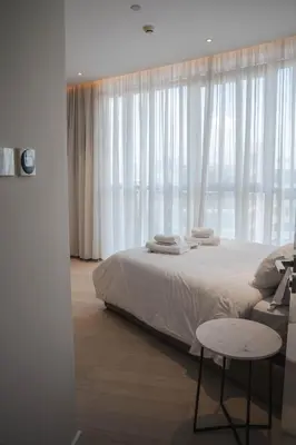 a bedroom with a bed and a window with white curtains at 360 Luxury One Bedroom Suite in Nicosia