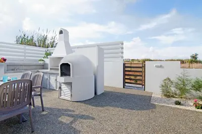 a white house with a fireplace on a patio at Thea Athena Villa - Walking to the Beach in Paralimni