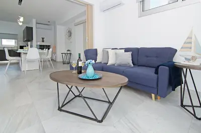 a living room with a blue couch and a table at Thea Athena Villa - Walking to the Beach in Paralimni