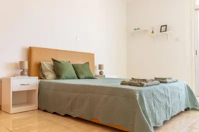a white bedroom with a bed with green pillows at Stunning apartment with sea view in Larnaka