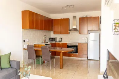 a kitchen with wooden cabinets and a wooden table at Stunning apartment with sea view in Larnaka