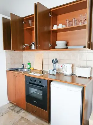 a kitchen with wooden cabinets and a black oven at Cozy Courtyard Apartment in Skarinou