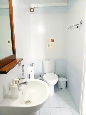 a white bathroom with a toilet and a sink at Cozy Courtyard Apartment in Skarinou