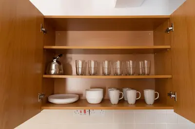 a pantry with wooden shelves with bowls and cups at Downtown apartment - Ayia Napa in Ayia Napa