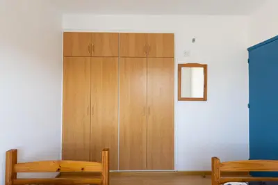 a room with a wooden cabinet and two benches at Downtown apartment - Ayia Napa in Ayia Napa