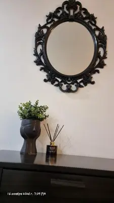 a mirror on a wall above a table with a vase at Deana beach in Limassol
