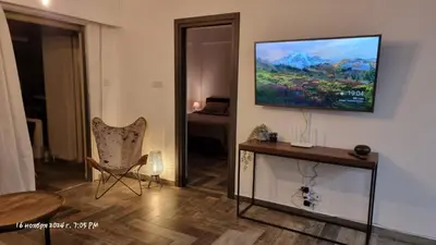 a living room with a chair and a television on the wall at Deana beach in Limassol