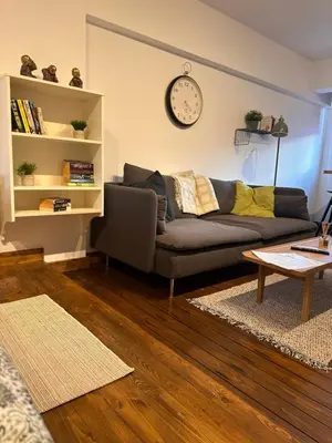 a living room with a couch and a clock on the wall at Cozzi Deluxe Studio in Voroklini
