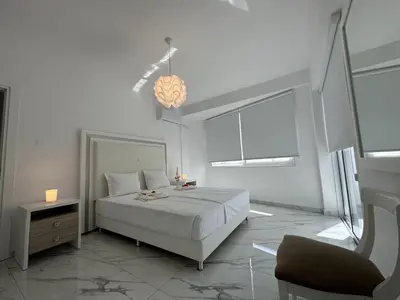 a white bedroom with a bed and a chair at Modern Seaside Retreat Near Nissi Beach in Ayia Napa